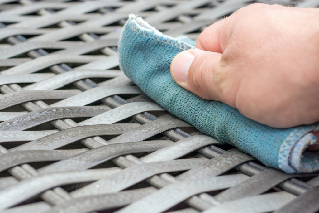 Close-up of a person cleaning outdoor furniture with a soft cloth.