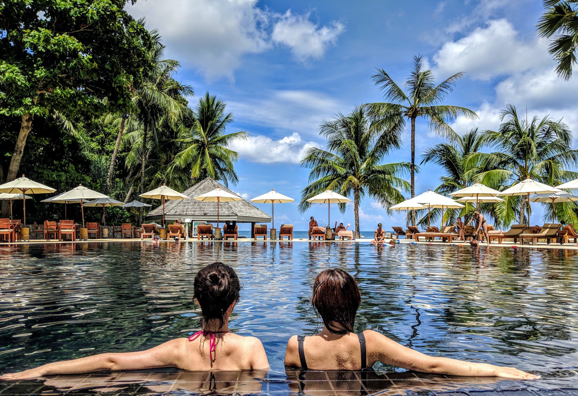 Two women relaxing by the pool on CG Outdoor furniture, enjoying a peaceful vacation moment2