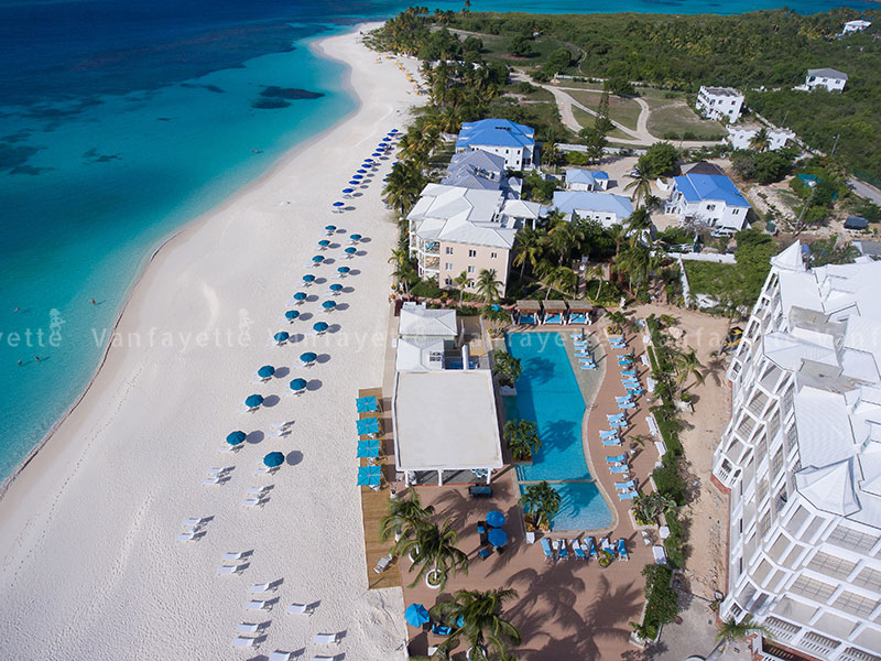Design Delivered – A Perfect Harmony of Product and Vision Aerial view of a beachside hotel furnished with CG Outdoor products, featuring blue-and-white umbrellas, sofas, and sunbeds