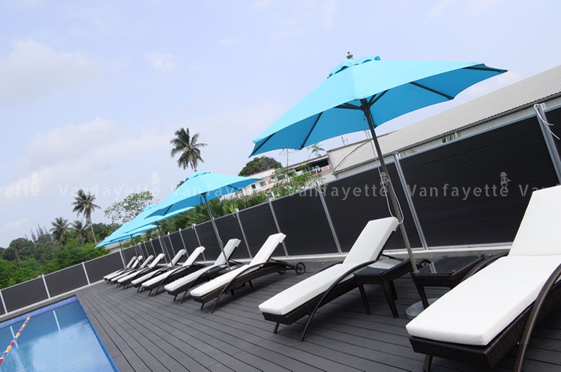 Function Meets Finish – Refined Poolside Practicality CG sun loungers with side tables and blue umbrellas arranged neatly around a poolside, highlighting commercial durability and uniformity Vanuatu
