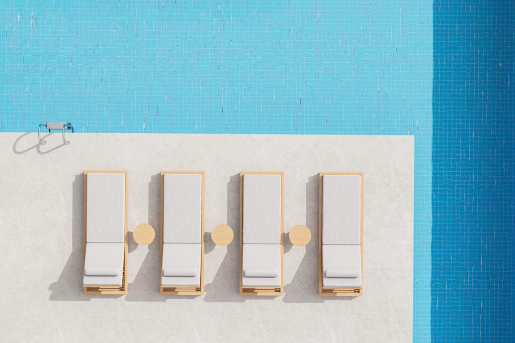 Top view of four outdoor sun loungers arranged beside a swimming pool with side tables and generous spacing.